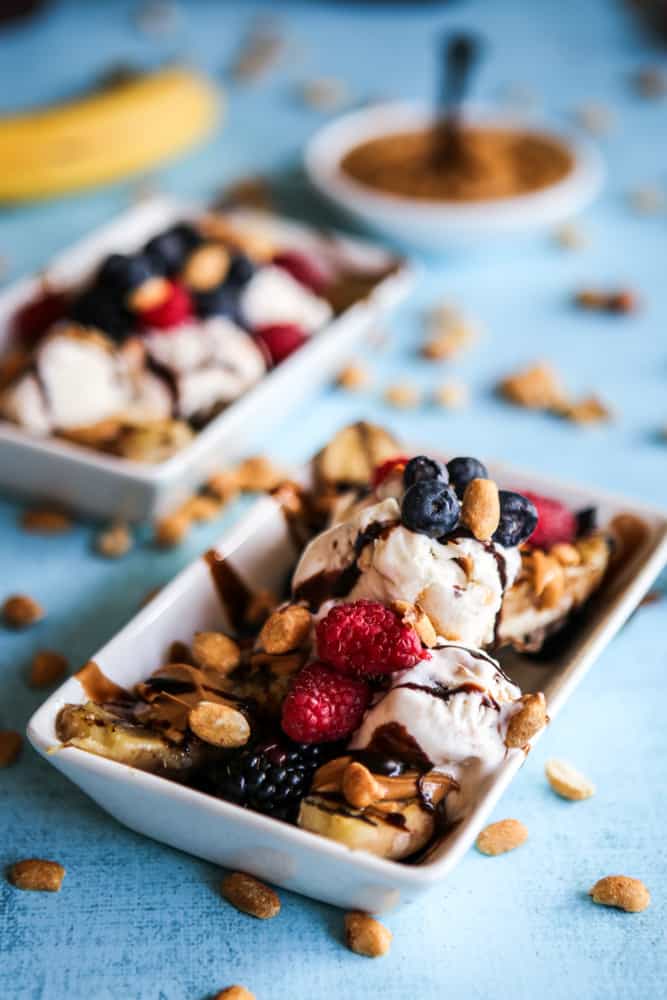 banana split in focus with plate of peanut butter and spoon in background