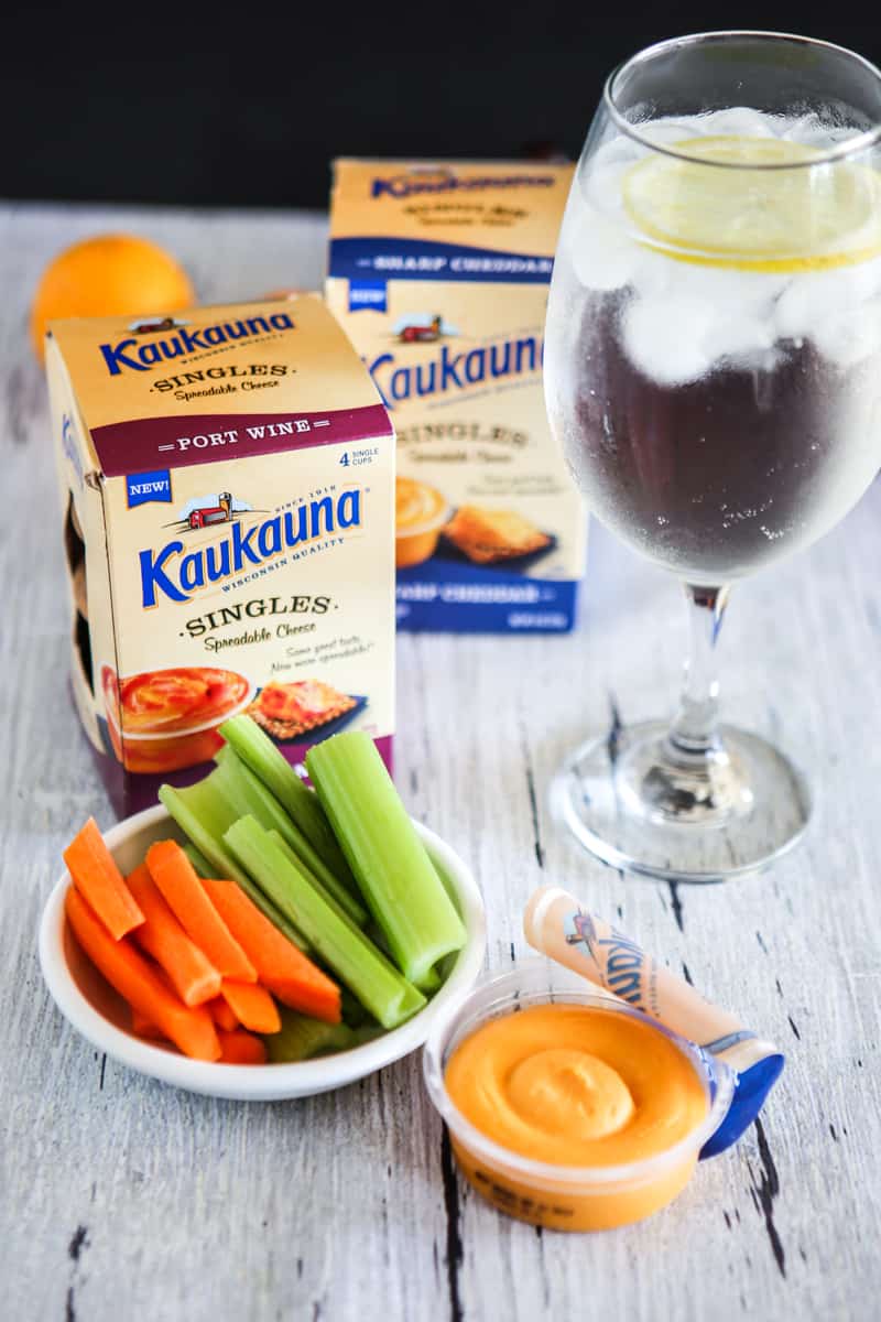 two boxes of kaukauna cheese singles with one open container and vegetables grey background
