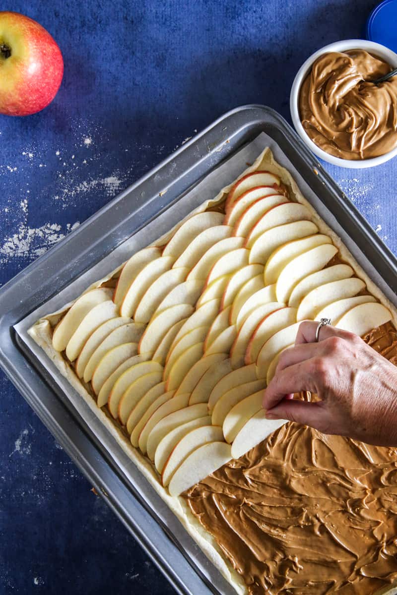 adding apple slices to peanut butter covered puff pastry