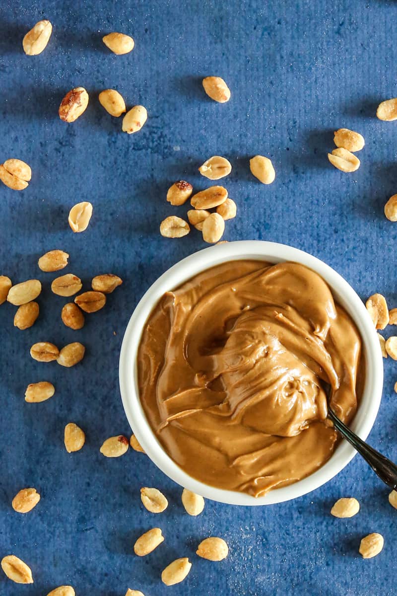 bowl of peanut butter peanut garnish on blue background