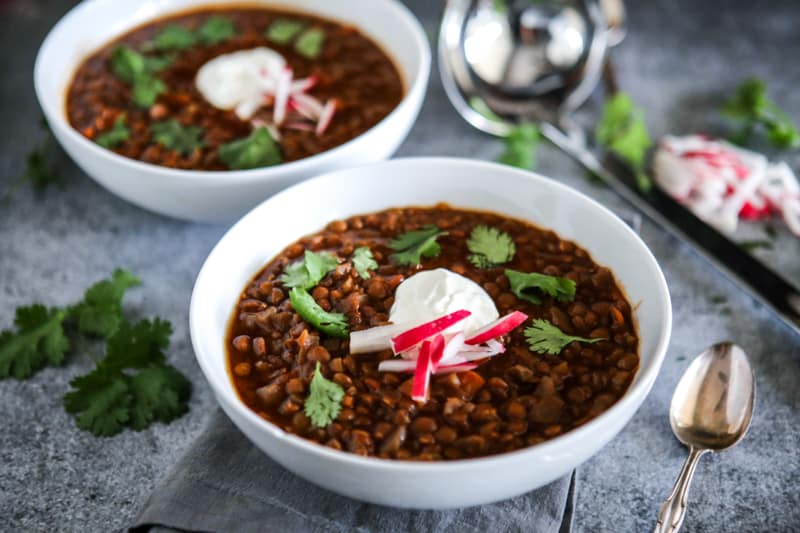 two bowls of chili with a spoon and soup ladle