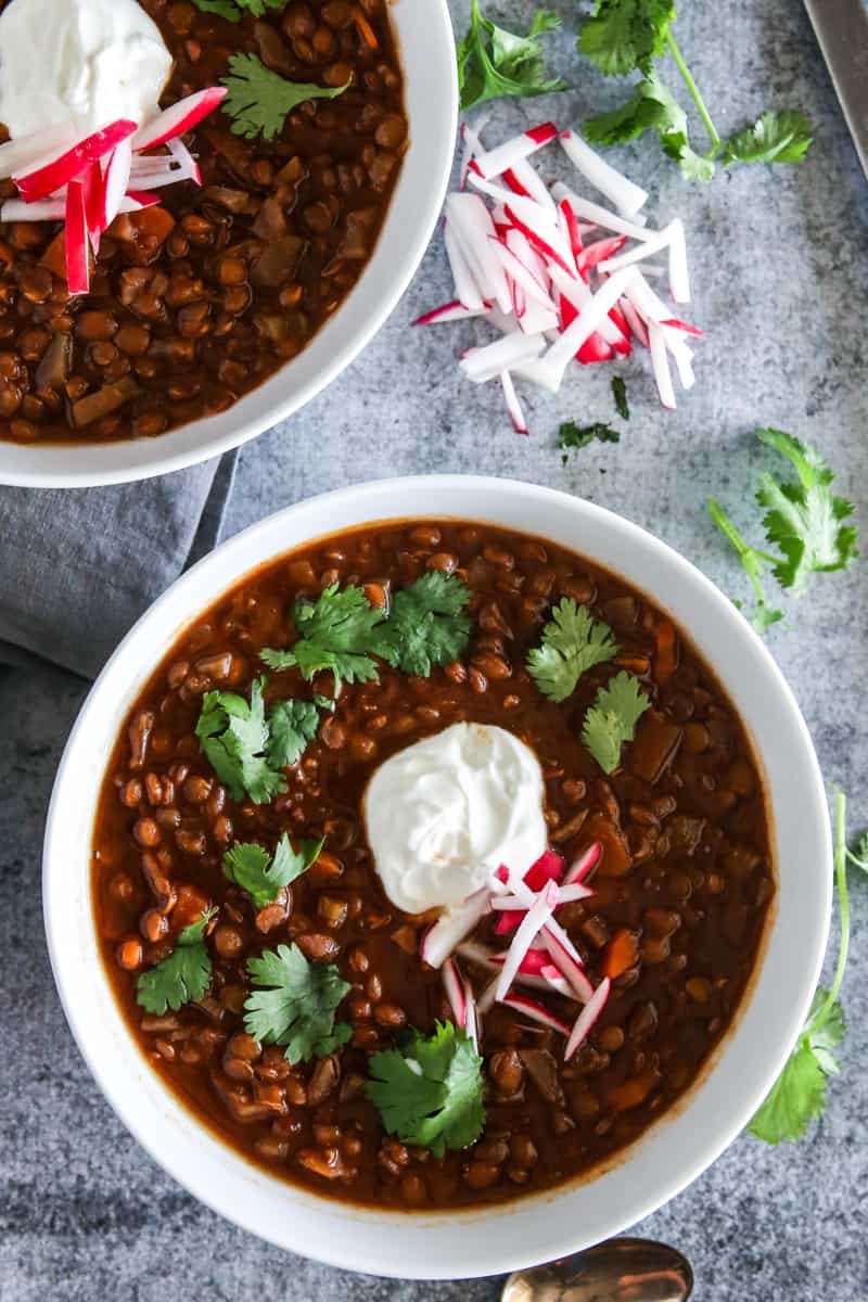 bowls of beet lentil chili and pile of radishes and cilantro